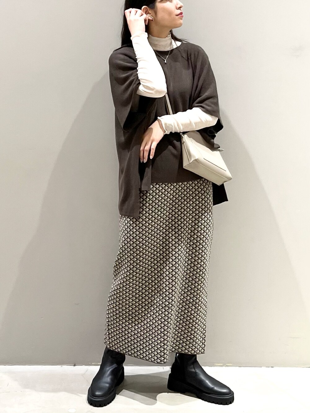 ブラウン系のスカート、ブラック系のブーツ、ブラウン系のニット/セーターを着用したレディースの秋コーディネートの5枚目の写真