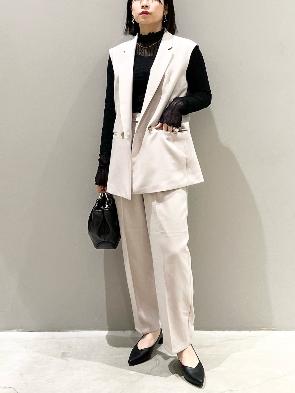 ブラック系のパンプス、ベージュ系のスラックス、ブラック系のハンドバッグを着用したレディースの冬コーディネートの5枚目の写真