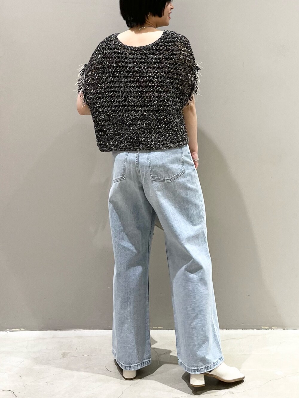 ブルー系のデニムパンツ、ホワイト系のサンダル、ホワイト系のショルダーバッグを着用したレディースの春コーディネートの3枚目の写真