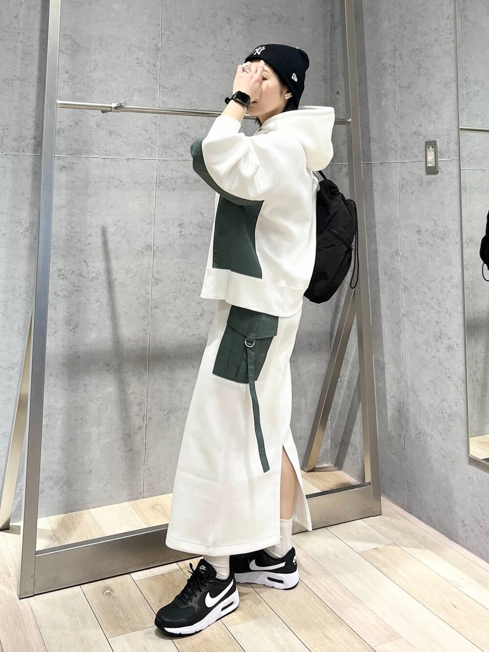 ブラック系のショルダーバッグ、ホワイト系のスカート、ホワイト系のパーカーを着用したレディースの冬コーディネートの5枚目の写真