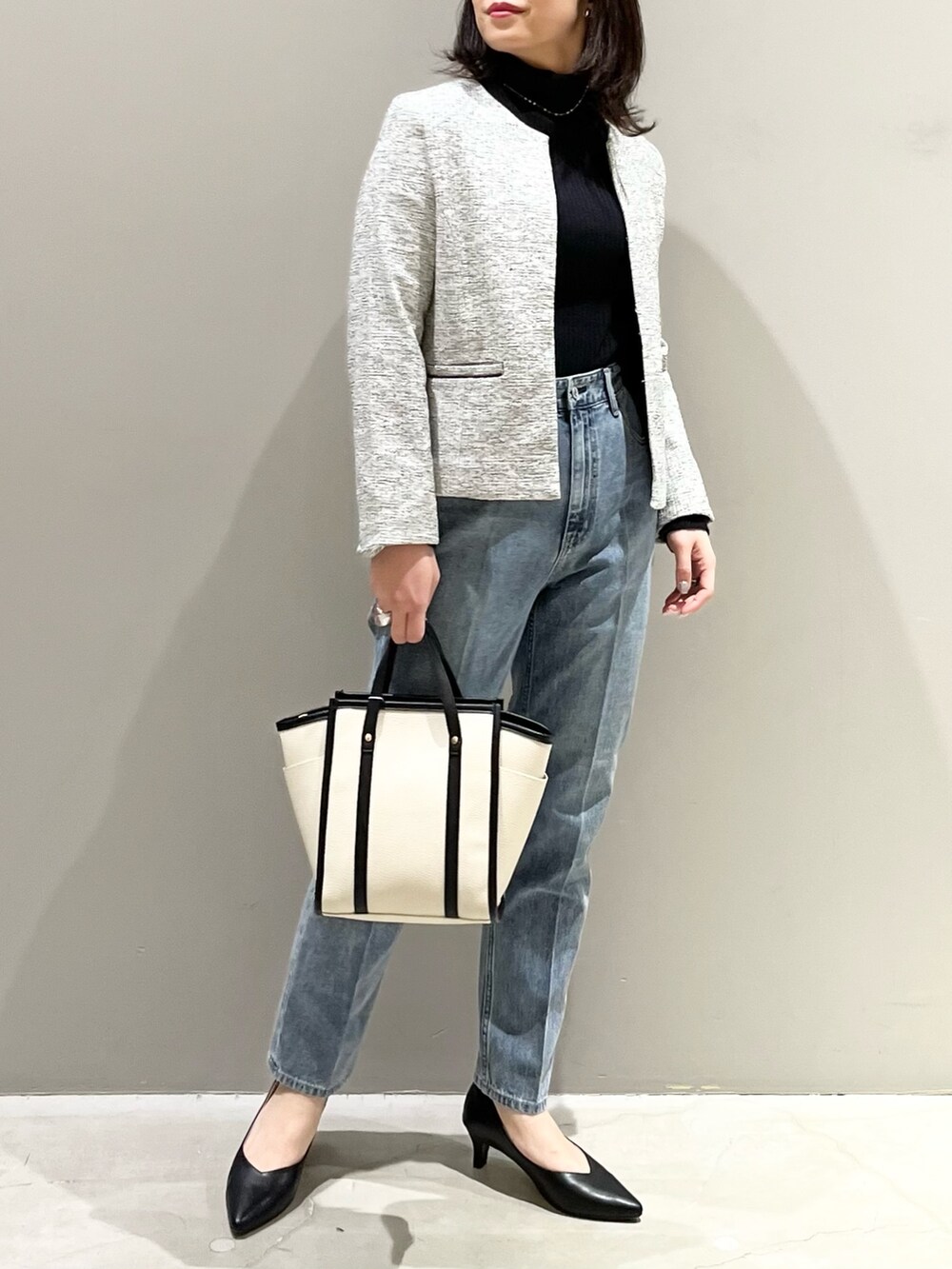 ブルー系のデニムパンツ、ブラック系のパンプス、ホワイト系のショルダーバッグを着用したレディースの冬コーディネートの2枚目の写真