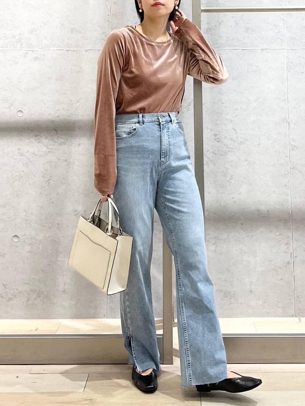 ブラック系のパンプス、ブルー系のデニムパンツ、ホワイト系のショルダーバッグを着用したレディースの秋コーディネートの2枚目の写真