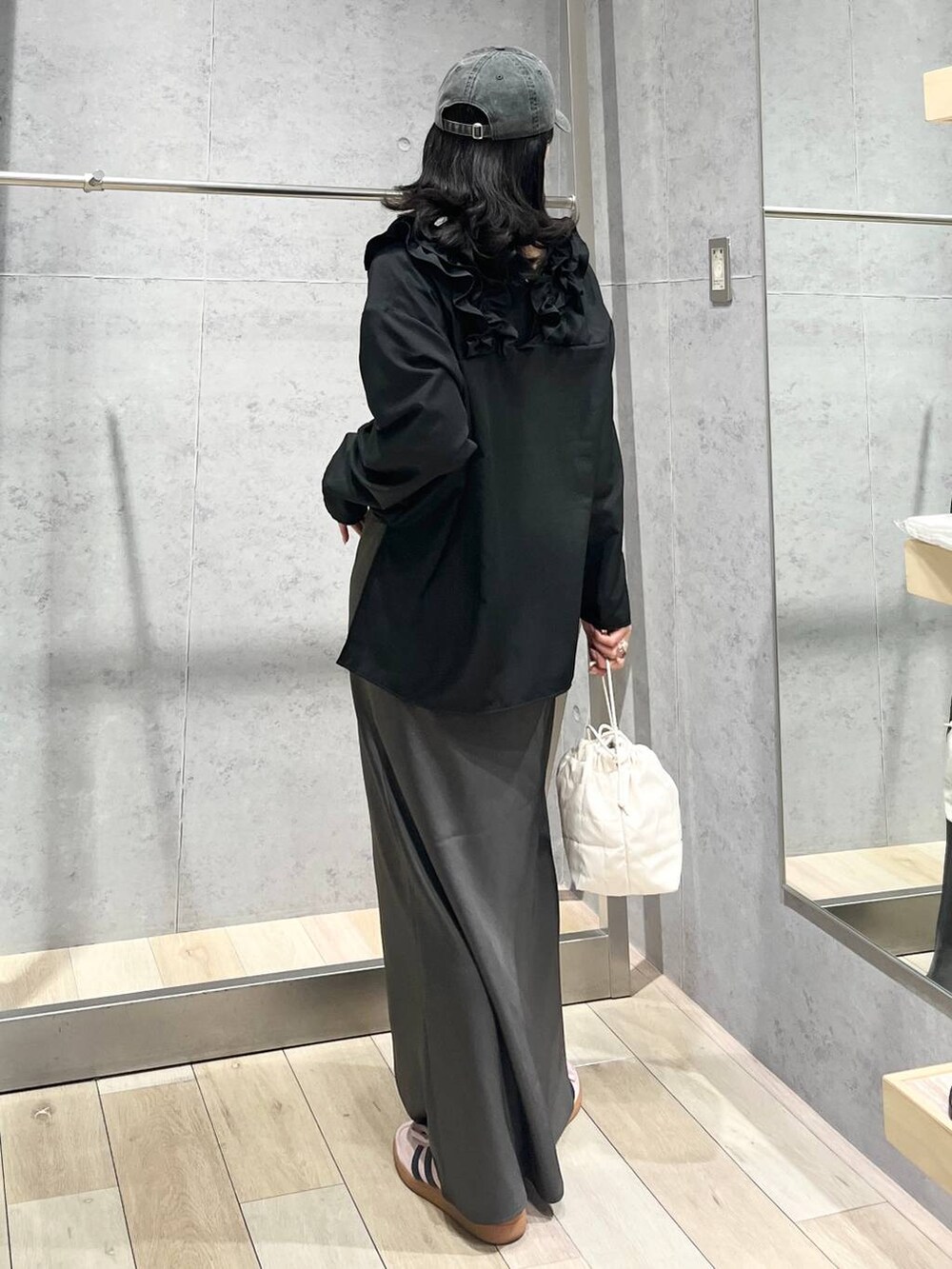 グレー系のスカート、ホワイト系のショルダーバッグ、ブラック系のキャップを着用したレディースの春コーディネートの5枚目の写真