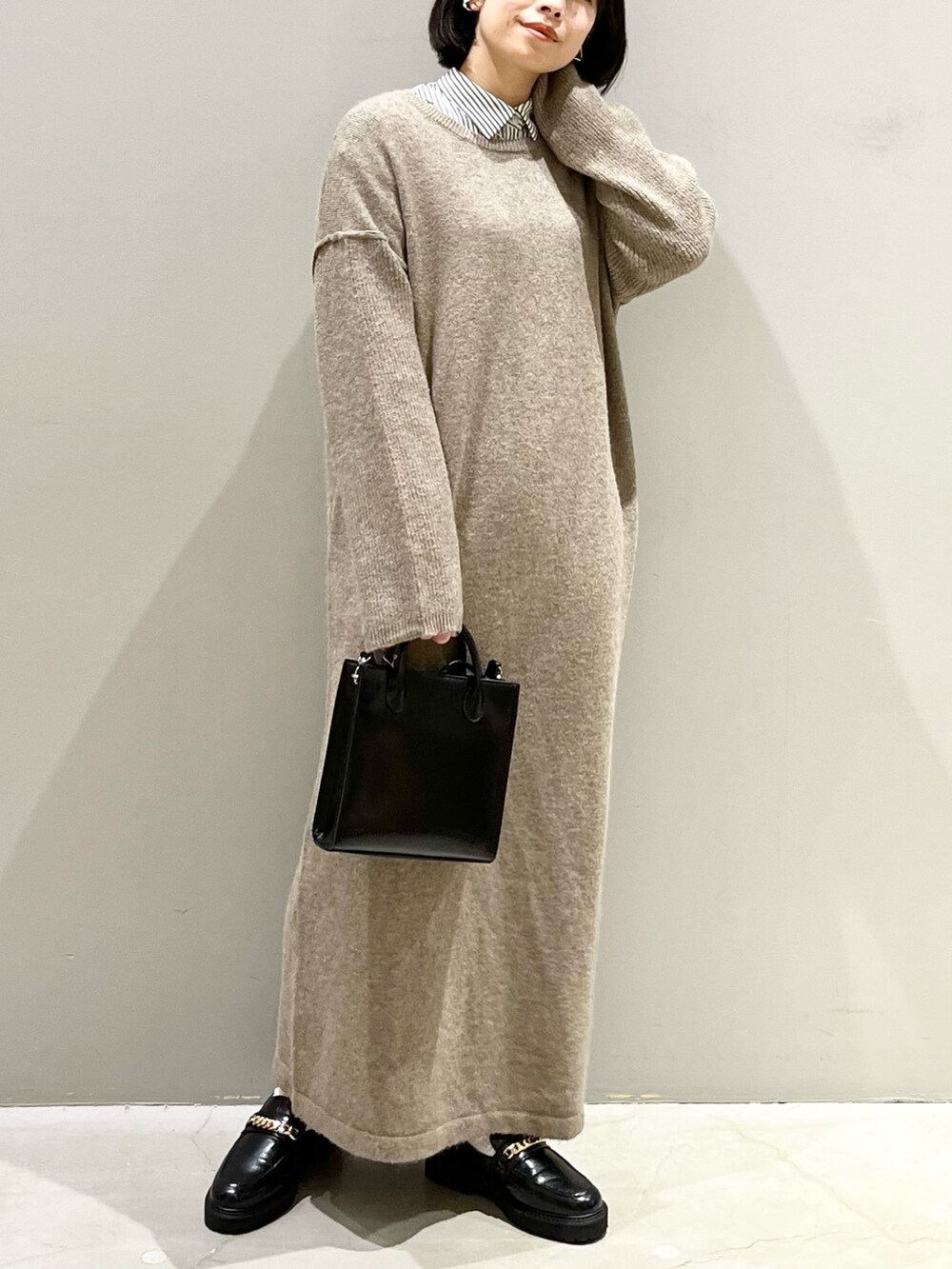 ブラック系のショルダーバッグ、ブラック系のローファー、ブラウン系のワンピースを着用したレディースの冬コーディネートの2枚目の写真