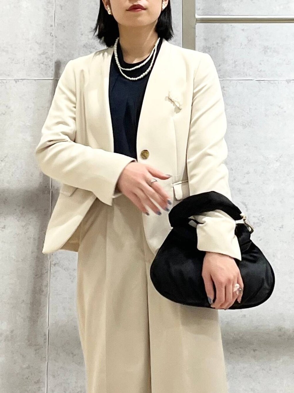 ブラック系のハンドバッグ、ブルー系のシャツ/ブラウス、ホワイト系のノーカラージャケットを着用したレディースの冬コーディネートの3枚目の写真