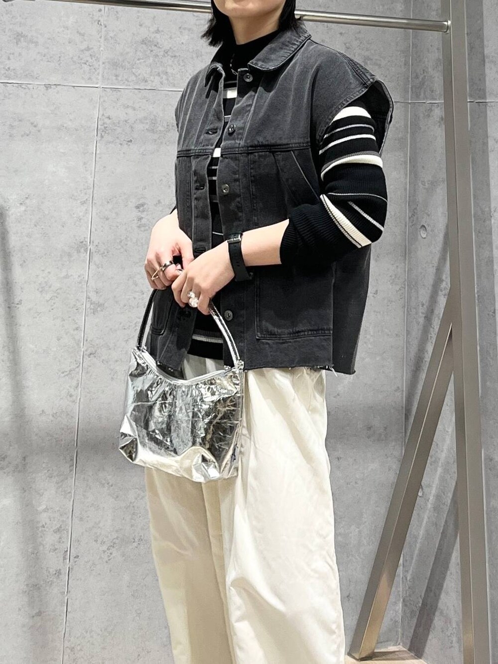 シルバー系のハンドバッグ、グレー系のベスト、ホワイト系のその他パンツを着用したレディースの冬コーディネートの4枚目の写真