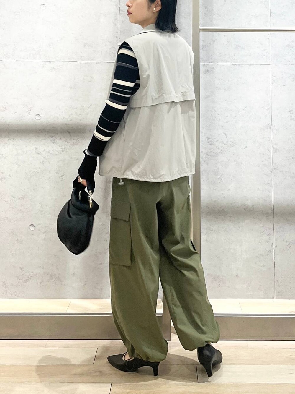 グレー系のベスト、ブラック系のハンドバッグ、グリーン系のカーゴパンツを着用したレディースの冬コーディネートの5枚目の写真