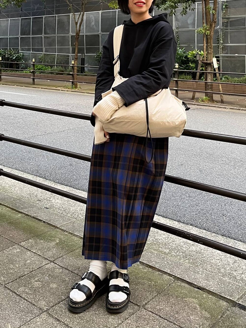 ブラック系のパーカー、ブルー系のスカート、ホワイト系のショルダーバッグを着用したレディースの秋コーディネートの6枚目の写真