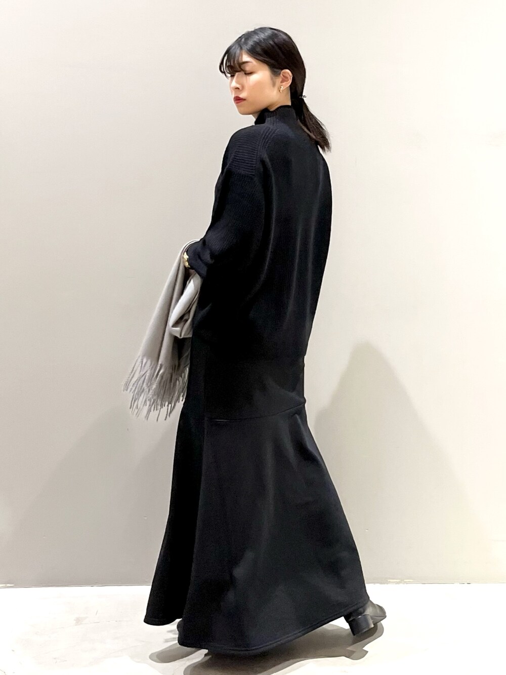 ブラック系のスカート、ブラック系のブーツ、ブラック系のニット/セーターを着用したレディースの秋コーディネートの4枚目の写真