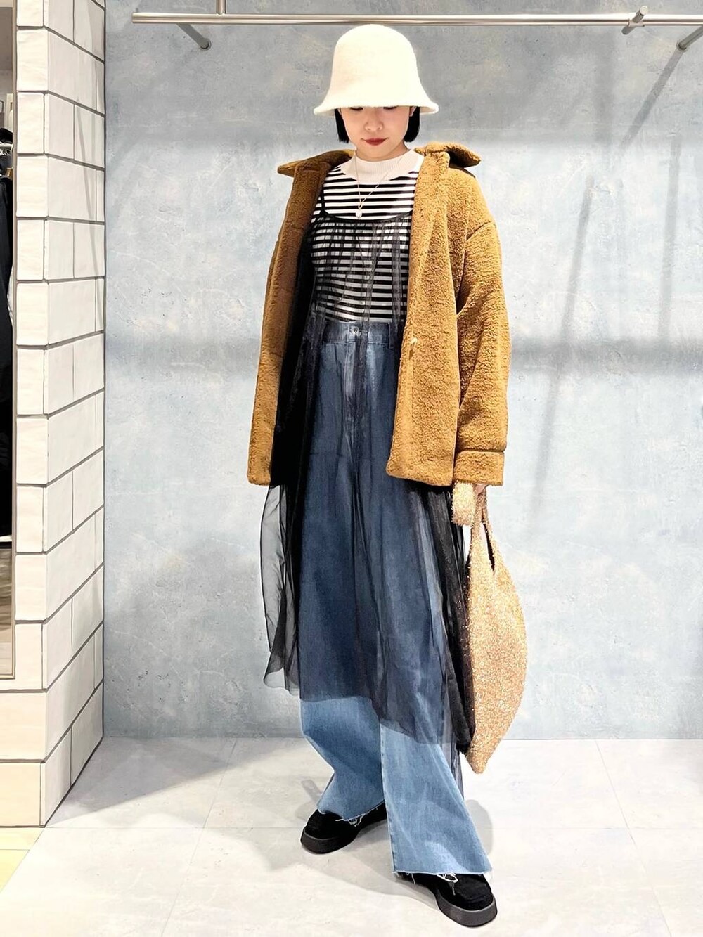 ブラウン系のブルゾン、ブラック系のモカシン/デッキシューズ、ゴールド系のショルダーバッグを着用したレディースの冬コーディネートの3枚目の写真