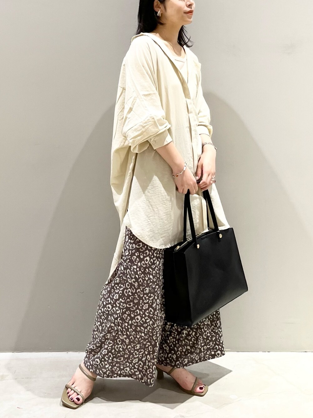 ブラック系のトートバッグ、ブラウン系のサンダル、ホワイト系のシャツ/ブラウスを着用したレディースの秋コーディネートの2枚目の写真