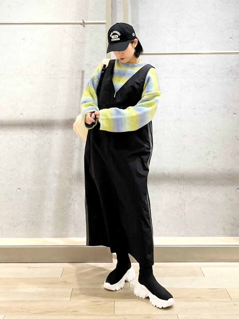 ホワイト系のバックパック/リュック、ブラック系のブーツ、ブラック系のジャンパースカートを着用したレディースの冬コーディネートの9枚目の写真