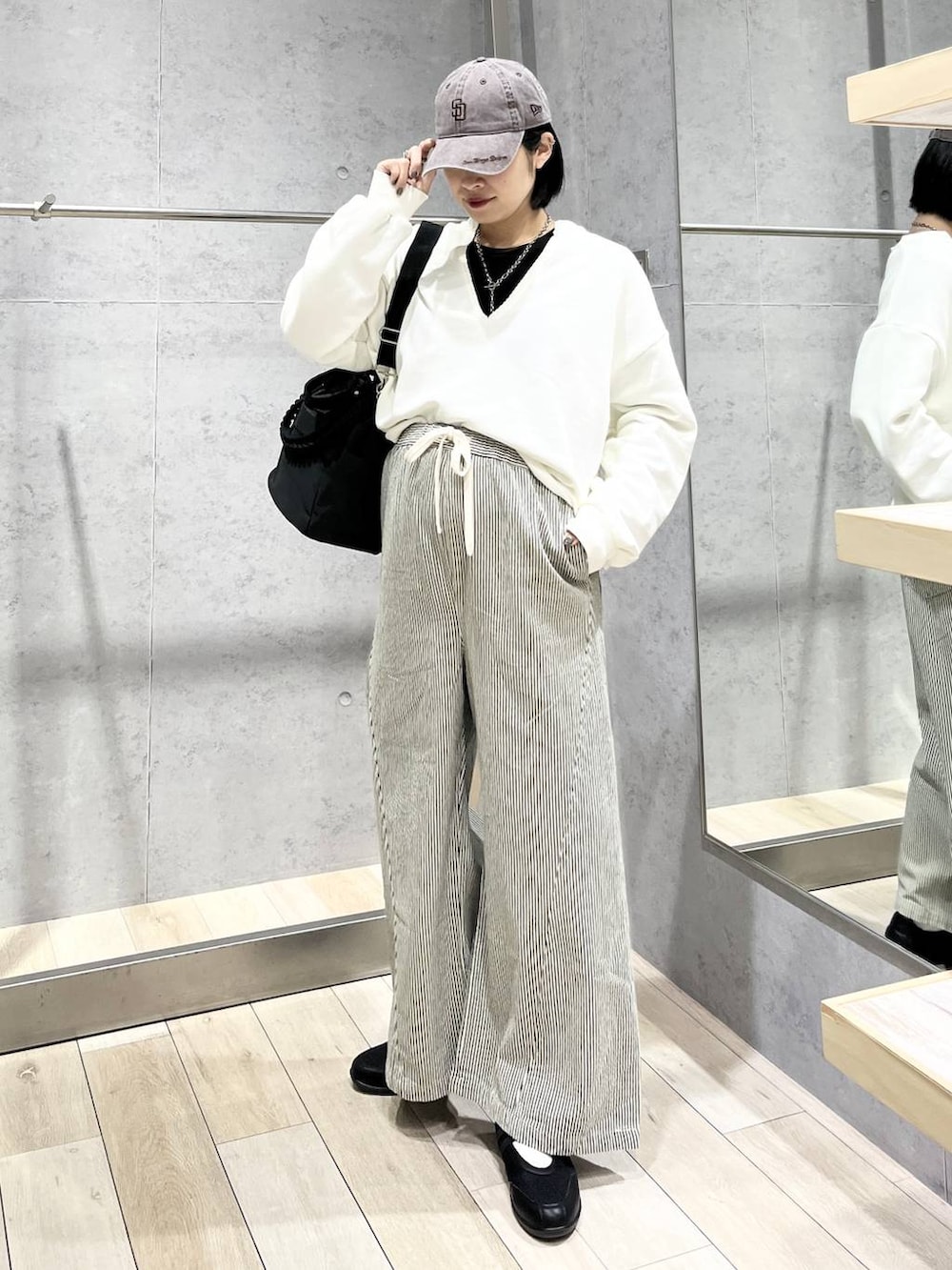 ブラック系のTシャツ/カットソー、ブラック系のショルダーバッグ、ブラック系のパンプスを着用したレディースの冬コーディネートの2枚目の写真