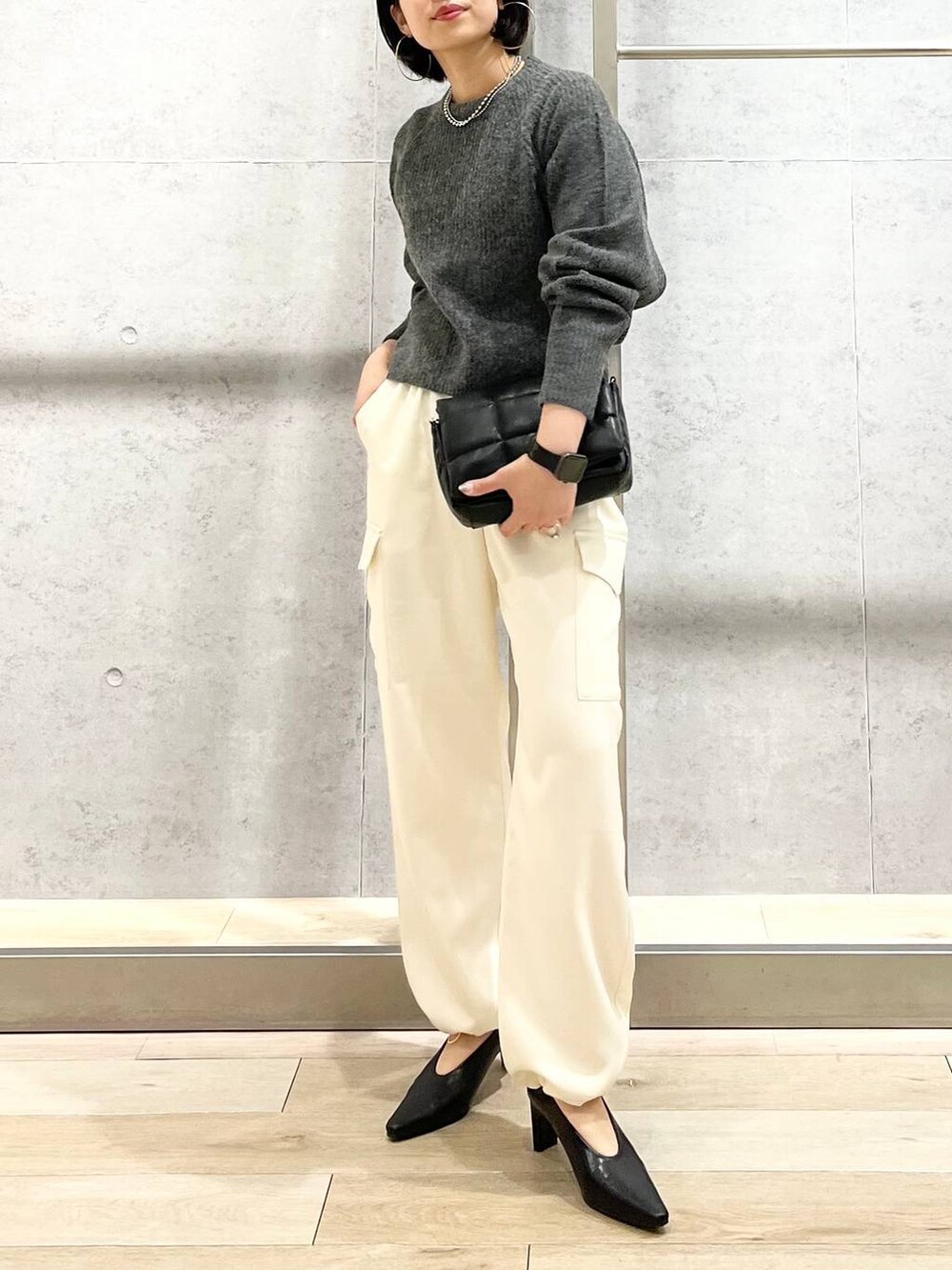 ブラック系のショルダーバッグ、ブラック系のパンプス、グレー系のニット/セーターを着用したレディースの秋コーディネートの2枚目の写真