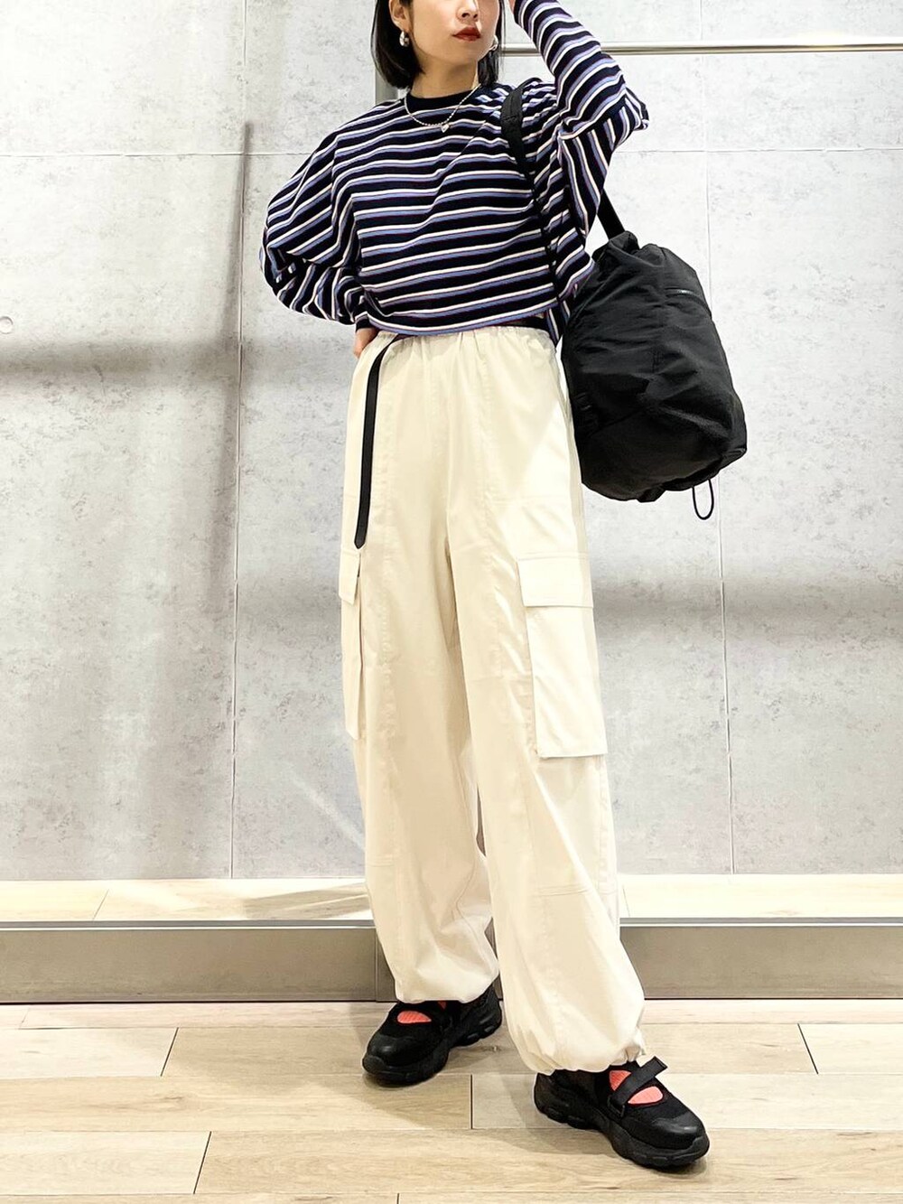 ブラック系のショルダーバッグ、ブルー系のTシャツ/カットソー、ホワイト系のカーゴパンツを着用したレディースの春コーディネートの6枚目の写真