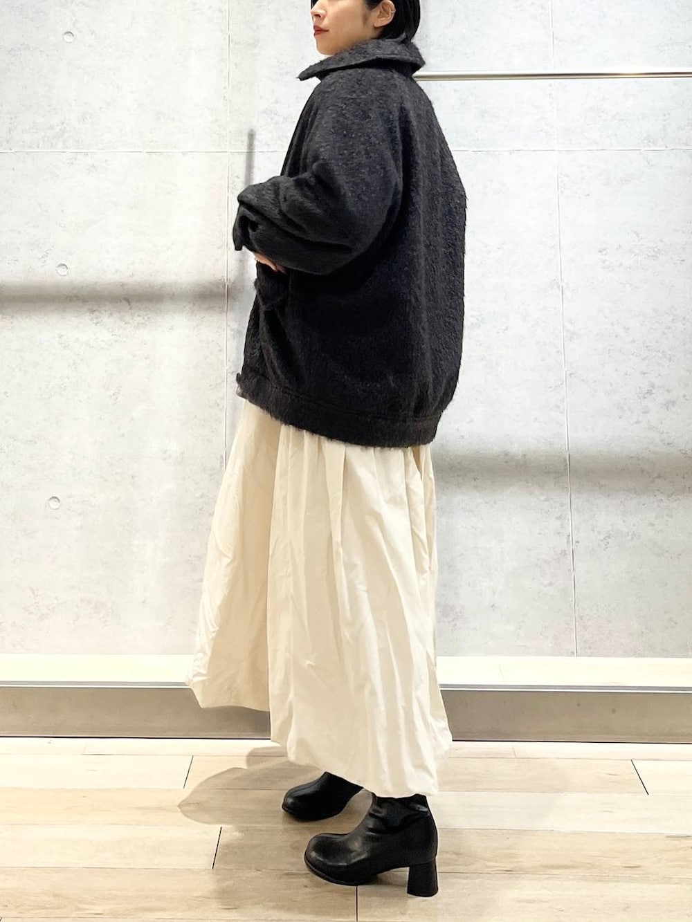 ブラック系のブーツ、ベージュ系のスカート、ブラック系のハンドバッグを着用したレディースの冬コーディネートの5枚目の写真