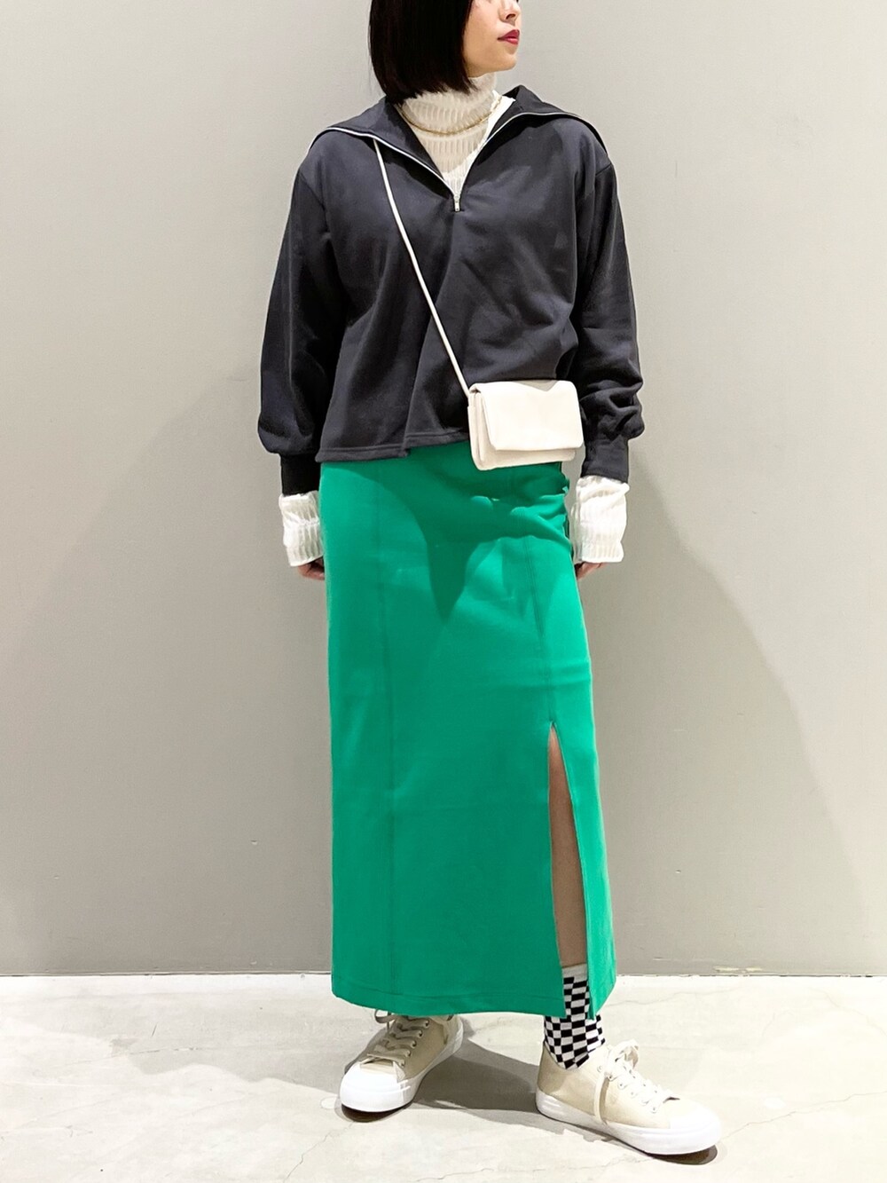 グリーン系のスカート、ベージュ系のスニーカー、ホワイト系のショルダーバッグを着用したレディースの春コーディネートの4枚目の写真