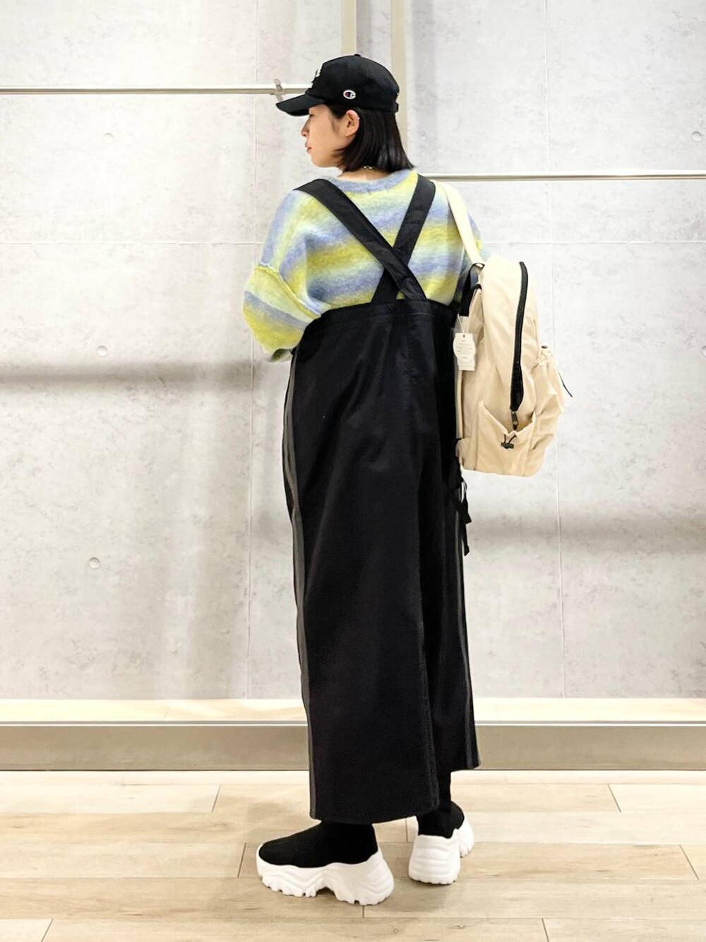 ホワイト系のバックパック/リュック、ブラック系のブーツ、ブラック系のジャンパースカートを着用したレディースの冬コーディネートの6枚目の写真