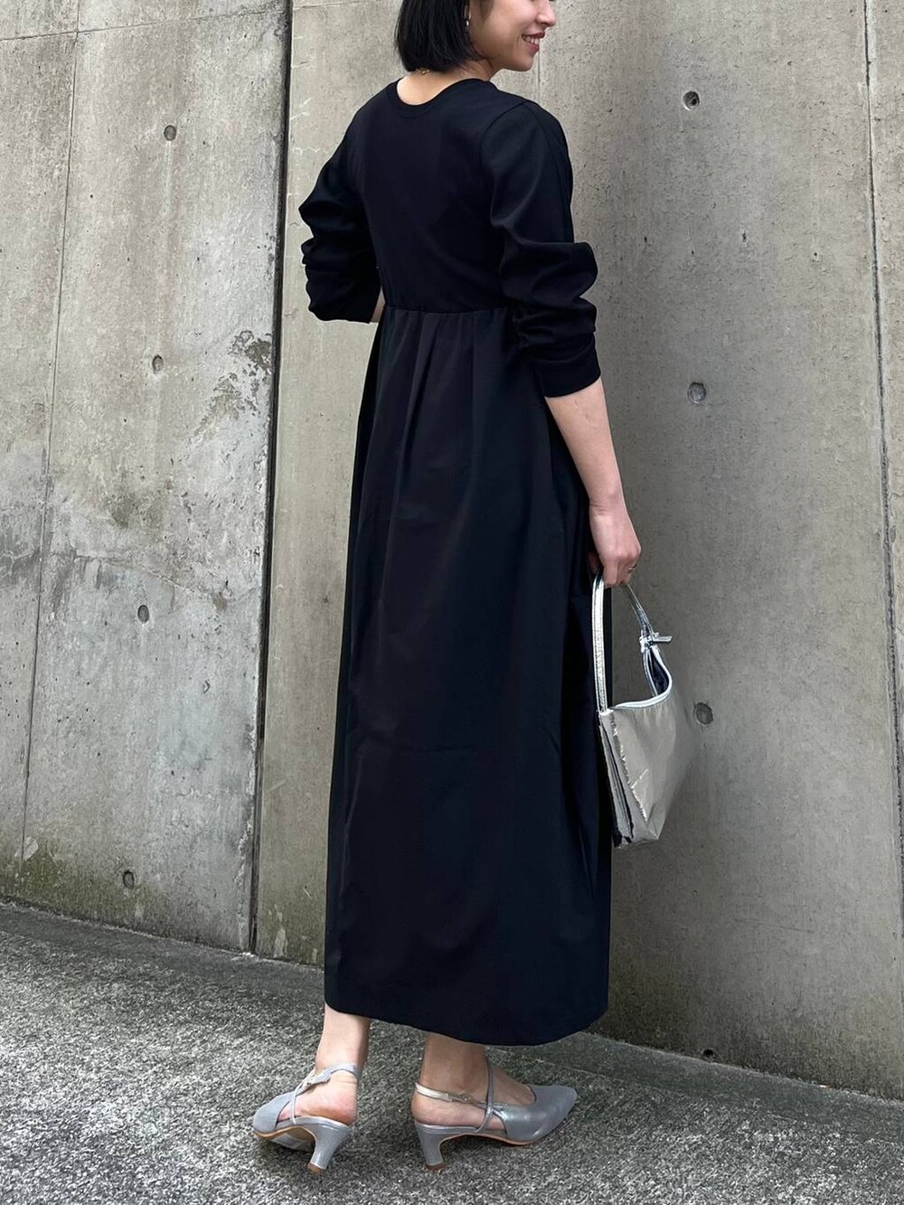 シルバー系のハンドバッグ、ブラック系のワンピース、グレー系のパンプスを着用したレディースの冬コーディネートの9枚目の写真