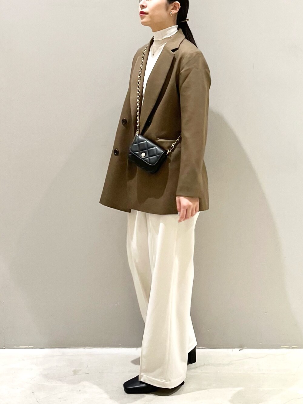 ホワイト系のスラックス、ブラック系のブーツ、ブラック系のバッグを着用したレディースの秋コーディネートの3枚目の写真