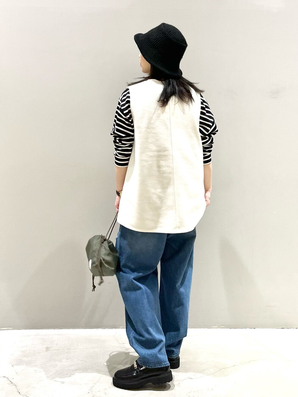 ブルー系のデニムパンツ、ブラック系のローファー、グリーン系のショルダーバッグを着用したレディースの冬コーディネートの3枚目の写真