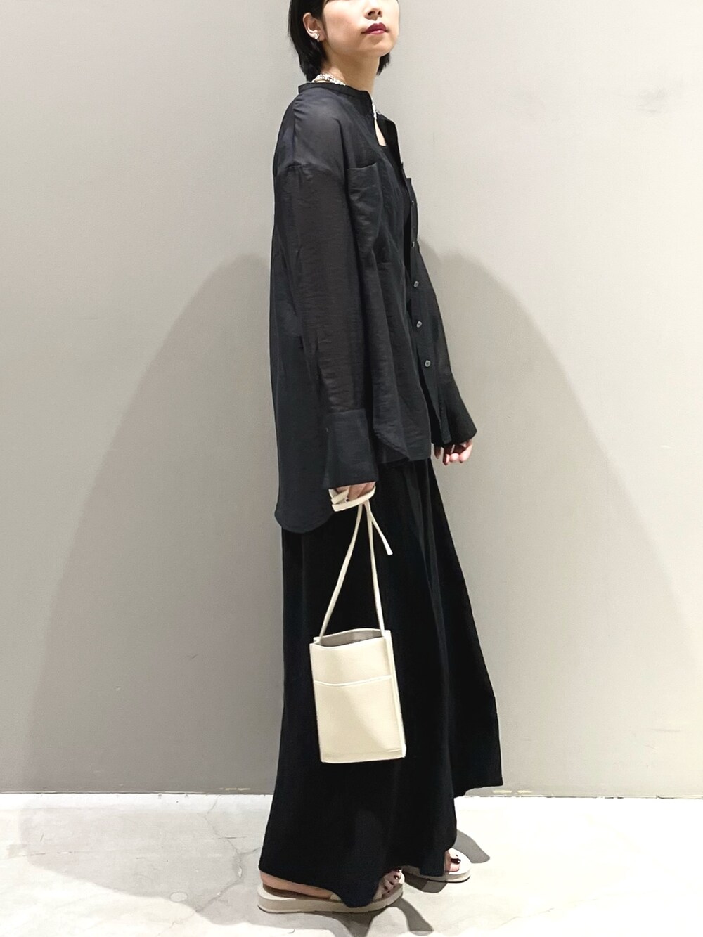 ホワイト系のサンダル、オレンジ系のバッグ、ブラック系のスカートを着用したレディースの夏コーディネートの5枚目の写真