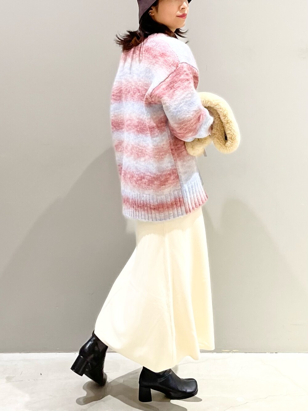 ブラック系のスカート、ブラック系のブーツ、パープル系のカーディガン/ボレロを着用したレディースの冬コーディネートの2枚目の写真