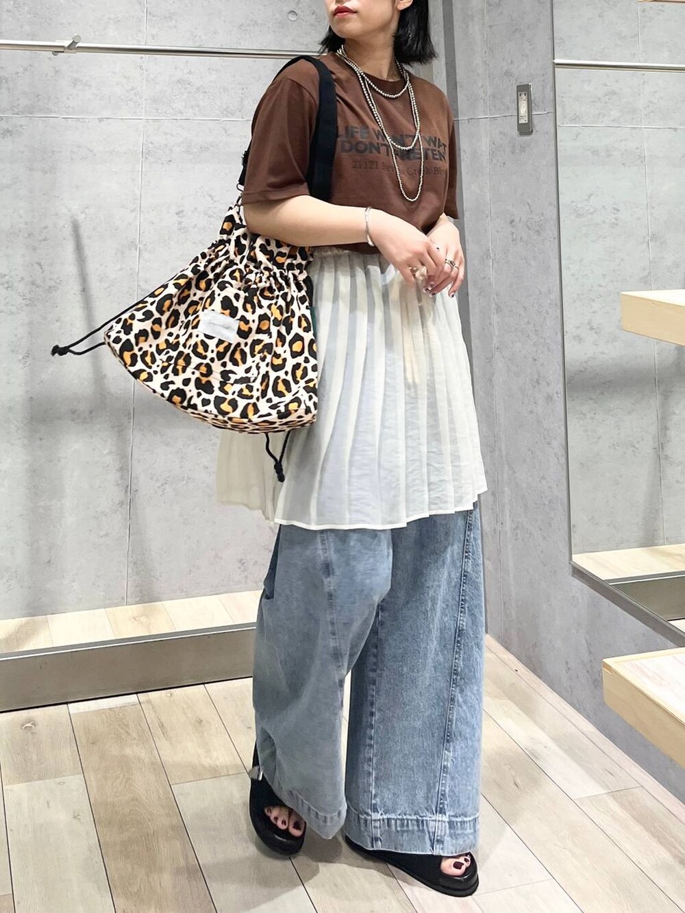 ブルー系のデニムパンツ、ブラック系のサンダル、シルバー系のネックレスを着用したレディースの夏コーディネートの3枚目の写真