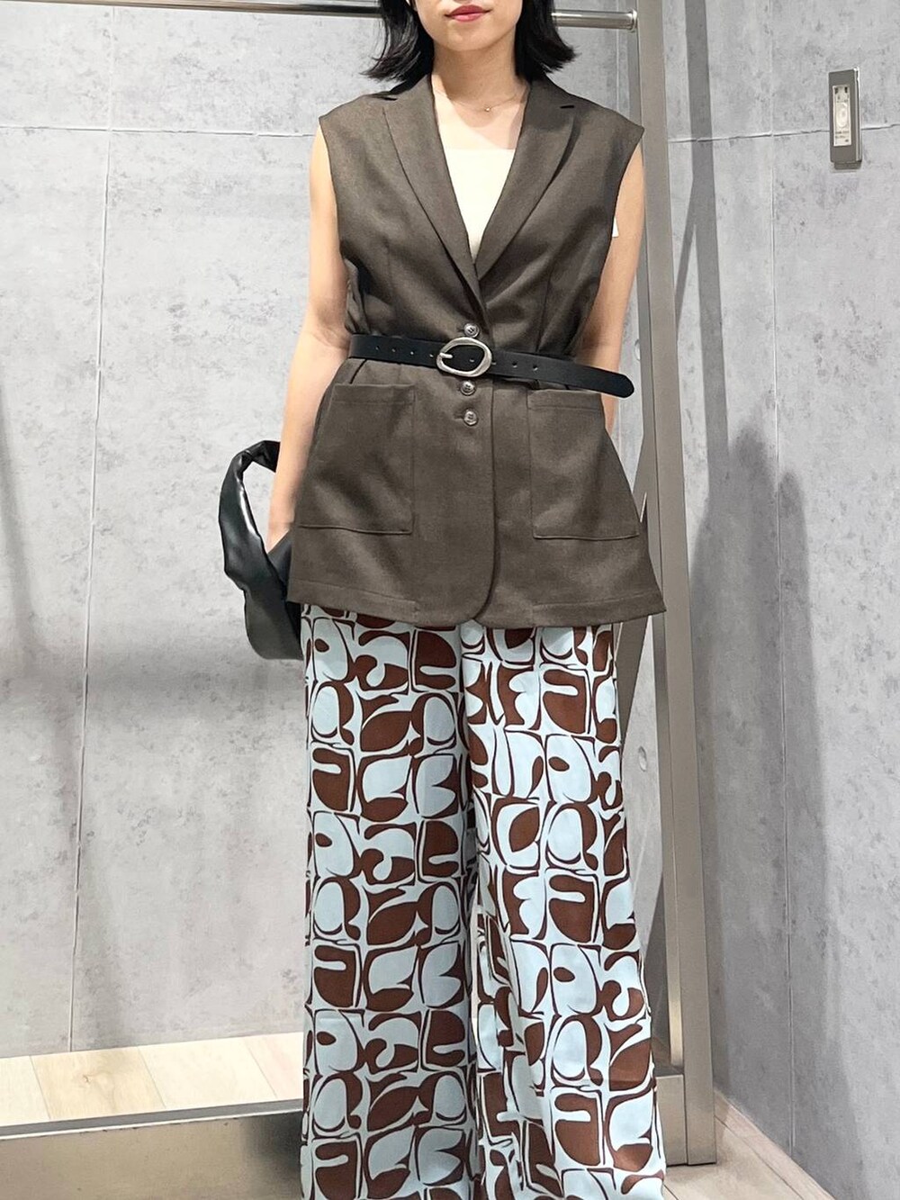 ホワイト系のタンクトップ、ホワイト系のサンダル、ブラック系のハンドバッグを着用したレディースの夏コーディネートの3枚目の写真