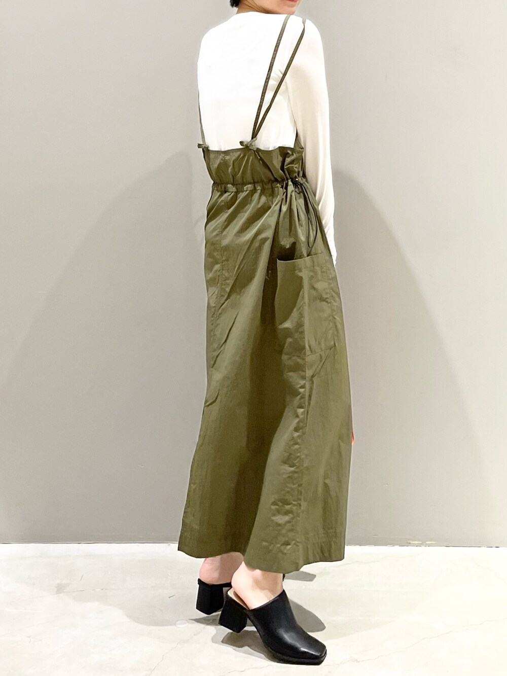 グリーン系のワンピース、オレンジ系のバッグ、ブラック系のサンダルを着用したレディースの春コーディネートの7枚目の写真