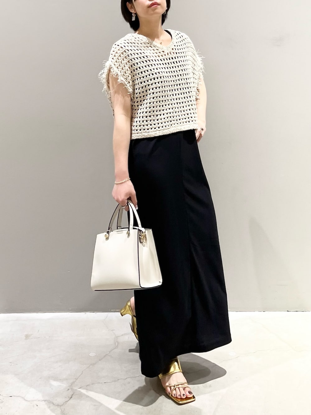 ホワイト系のショルダーバッグ、ブラック系のジャンパースカート、ゴールド系のサンダルを着用したレディースの夏コーディネートの5枚目の写真