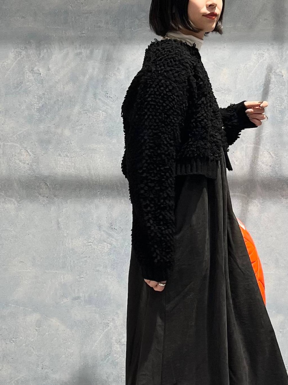 オレンジ系のトートバッグ、グレー系のワンピース、ブラック系のブーツを着用したレディースの冬コーディネートの2枚目の写真