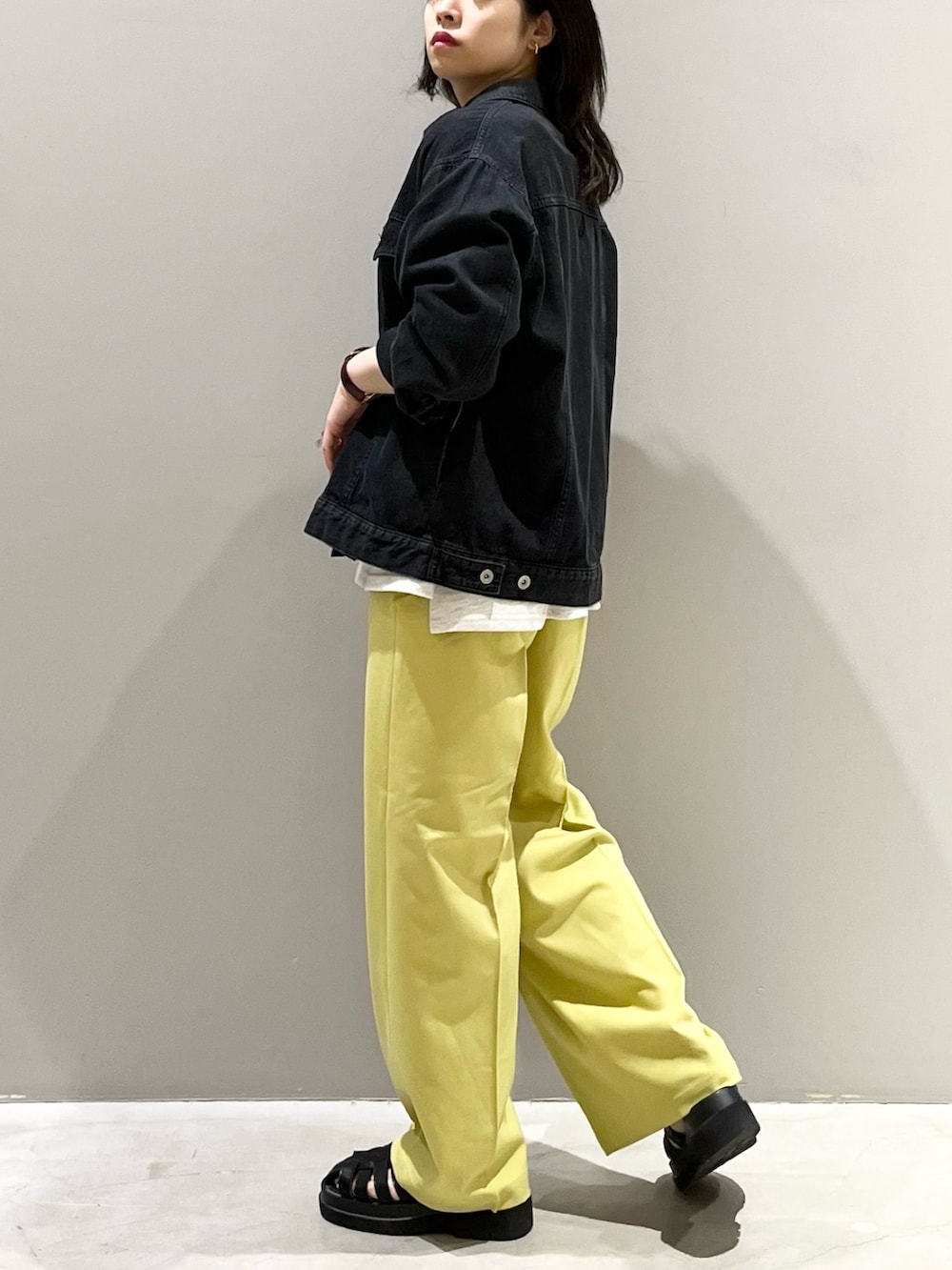 イエロー系のスラックス、ブラック系のサンダル、ベージュ系のTシャツ/カットソーを着用したレディースの秋コーディネートの3枚目の写真