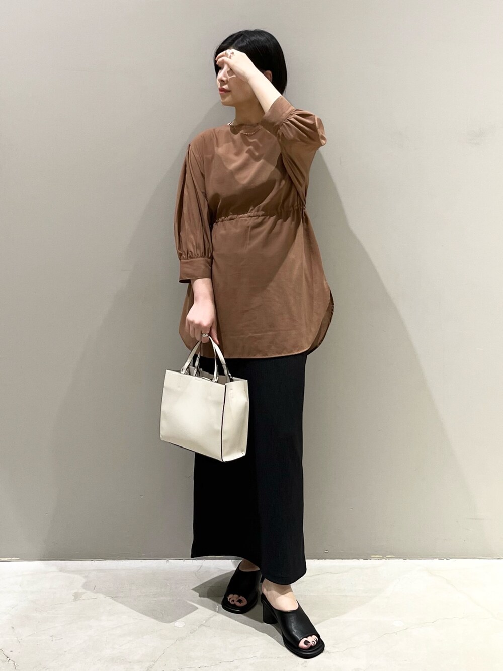 イエロー系のシャツ/ブラウス、ブラック系のスカート、ブラウン系のバッグを着用したレディースの秋コーディネートの6枚目の写真