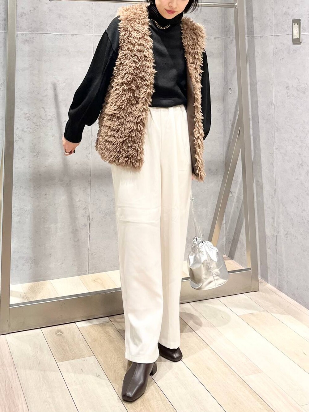 ブラック系のニット/セーター、ブラウン系のブーツ、ホワイト系のその他パンツを着用したレディースの秋コーディネートの7枚目の写真