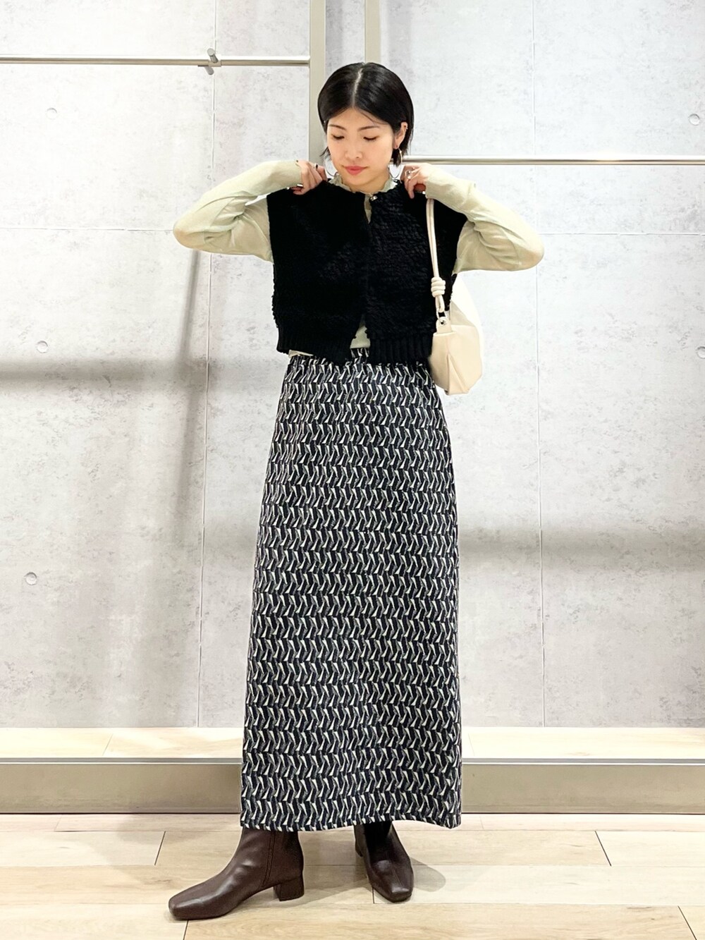 グリーン系のスカート、グリーン系のTシャツ/カットソー、ブラック系のベストを着用したレディースの秋コーディネートの2枚目の写真