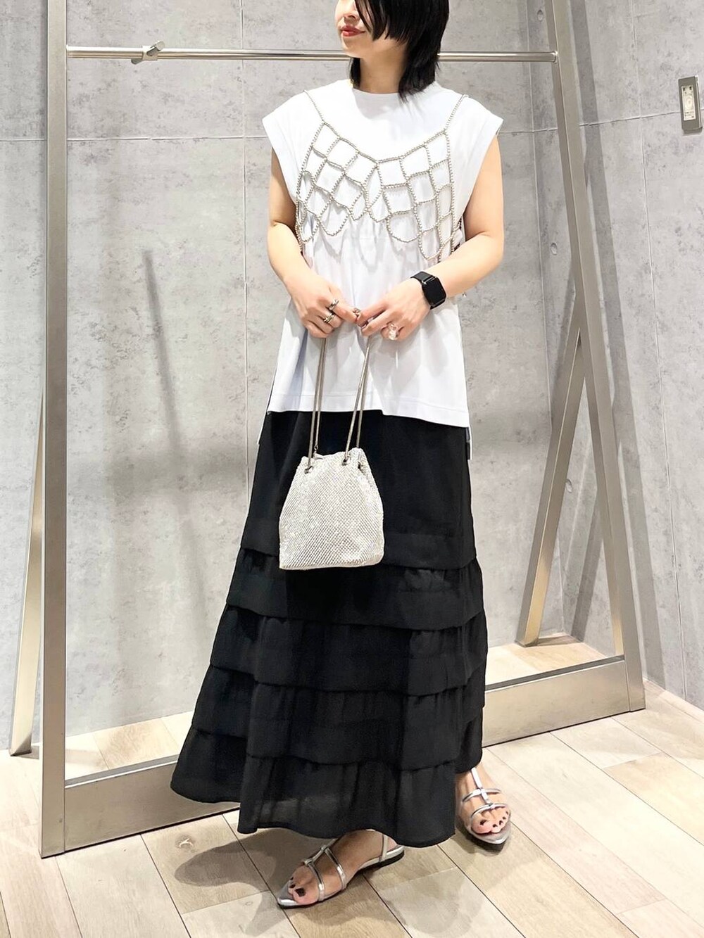 シルバー系のショルダーバッグ、ブルー系のTシャツ/カットソー、シルバー系のサンダルを着用したレディースの夏コーディネートの2枚目の写真