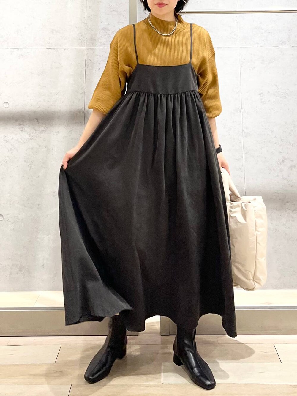 ブラウン系のニット/セーター、ホワイト系のショルダーバッグ、ブラック系のブーツを着用したレディースの秋コーディネートの3枚目の写真