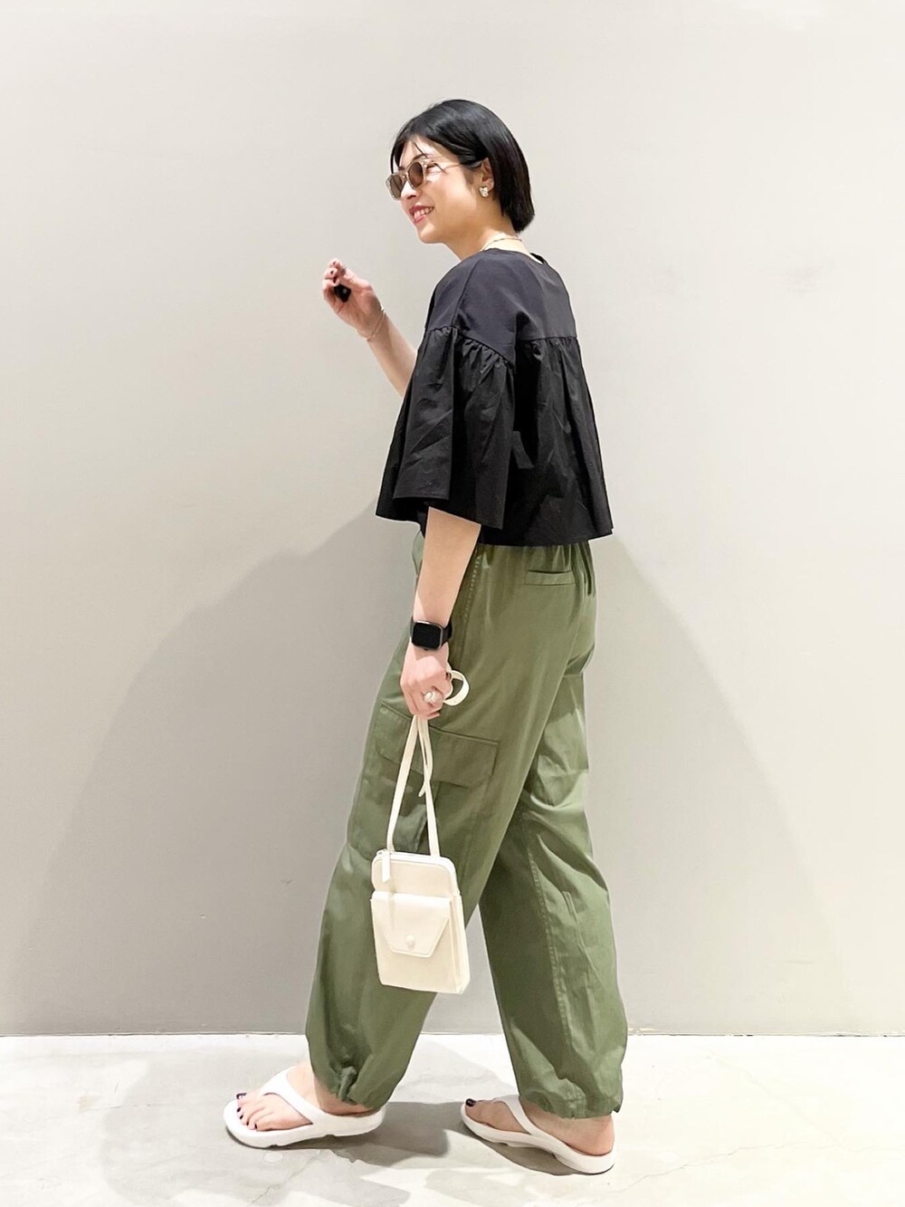 グリーン系のパンツ、ブラック系のTシャツ/カットソー、ホワイト系のショルダーバッグを着用したレディースの春コーディネートの3枚目の写真