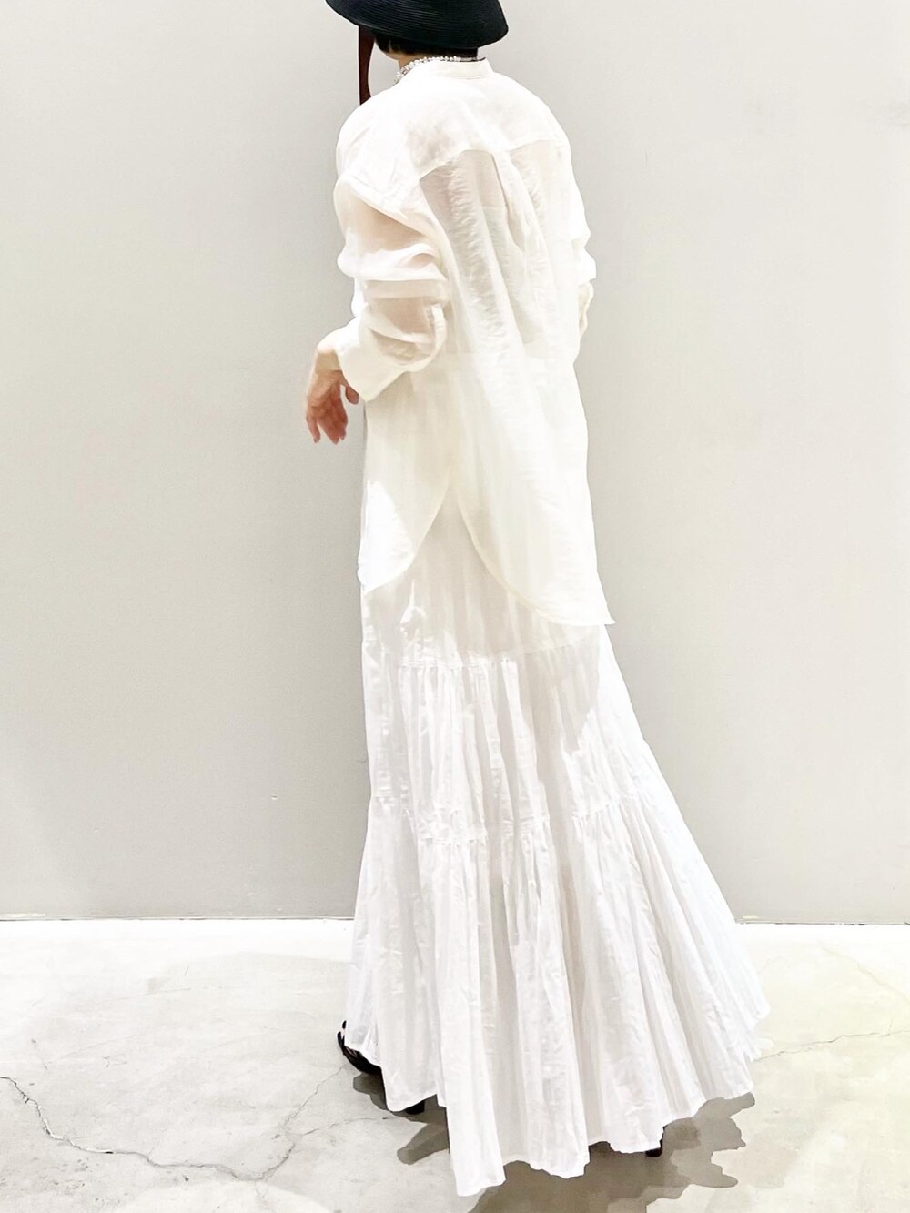 ホワイト系のスカート、ホワイト系のシャツ/ブラウス、ブラック系のサンダルを着用したレディースの夏コーディネートの2枚目の写真