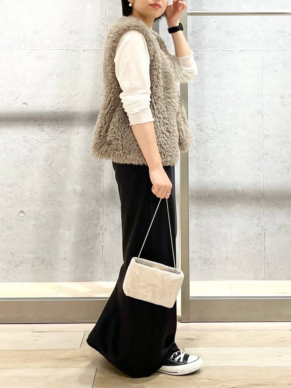 ブラック系のキャミソール、ベージュ系のベスト、ホワイト系のTシャツ/カットソーを着用したレディースの秋コーディネートの5枚目の写真