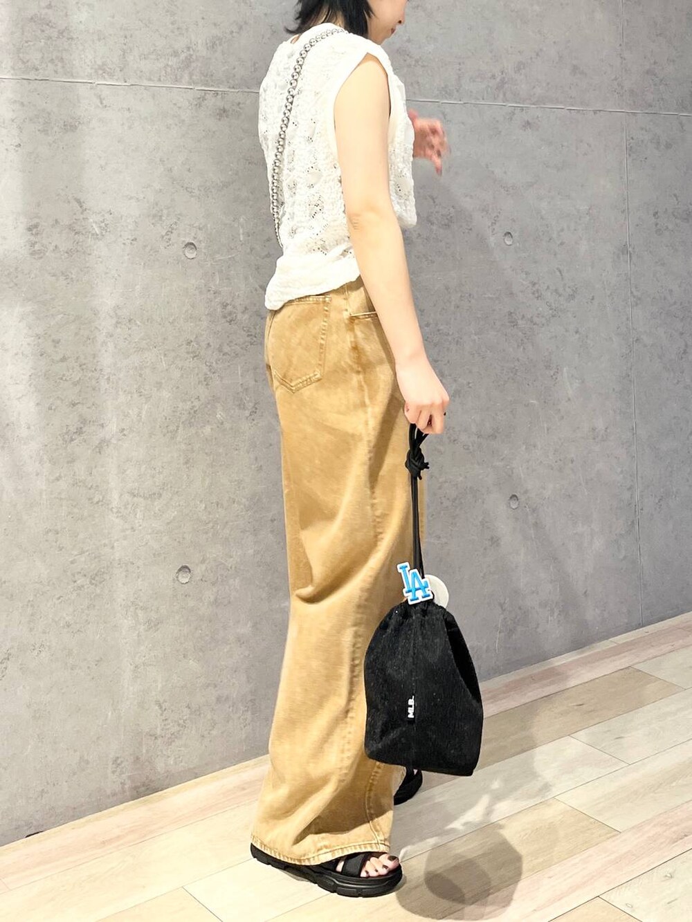 ブラック系のショルダーバッグ、ブラウン系のデニムパンツ、ブラック系のサンダルを着用したレディースの夏コーディネートの3枚目の写真