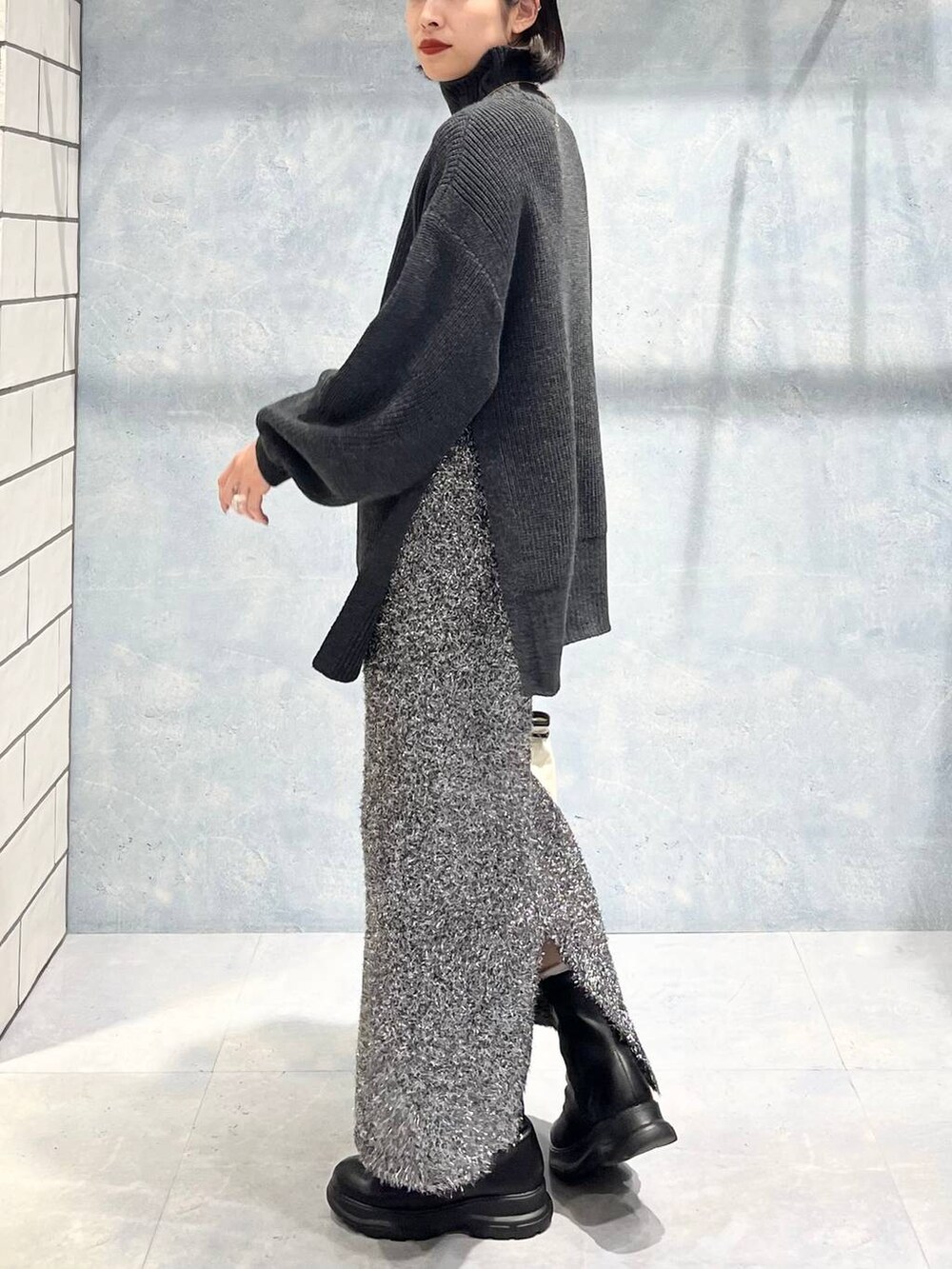 グレー系のTシャツ/カットソー、ブラック系のブーツ、ブラック系のスカートを着用したレディースの冬コーディネートの2枚目の写真