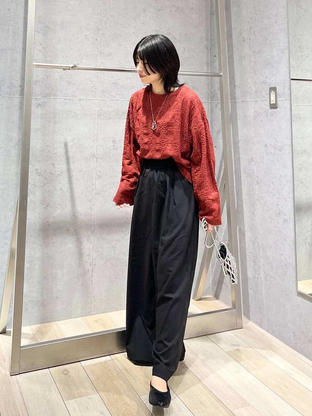 レッド系のTシャツ/カットソー、ブラック系のスラックス、シルバー系のショルダーバッグを着用したレディースの夏コーディネートの3枚目の写真