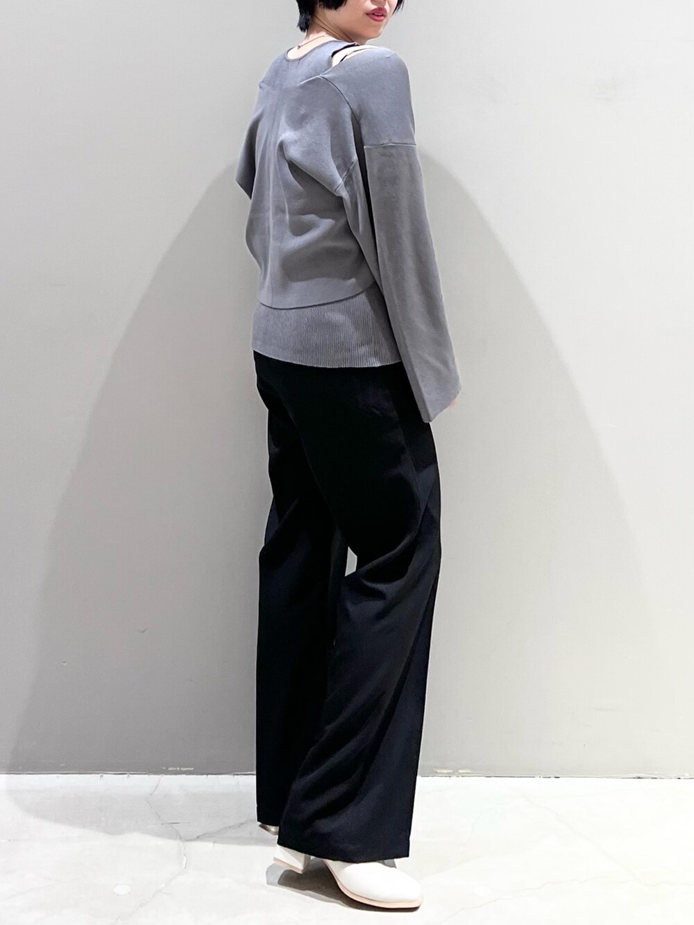 グレー系のニット/セーター、ブラック系のパンツ、ホワイト系のシューズを着用したレディースの春コーディネートの5枚目の写真