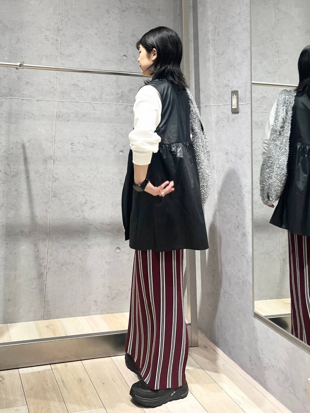 シルバー系のショルダーバッグ、レッド系のスカート、ブラック系のワンピースを着用したレディースの秋コーディネートの7枚目の写真