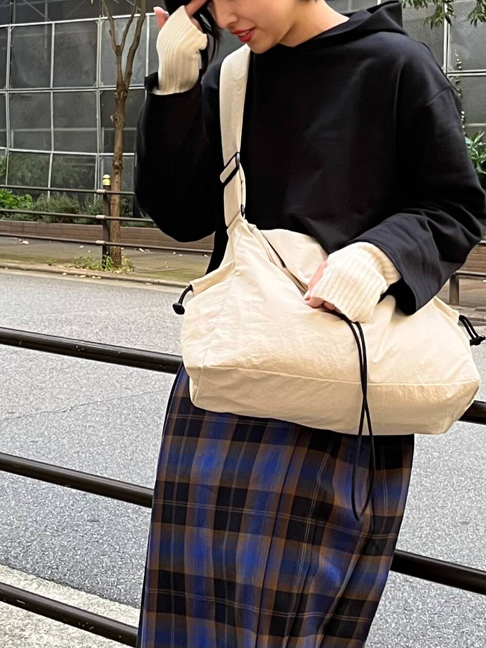 ブラック系のパーカー、ブルー系のスカート、ホワイト系のショルダーバッグを着用したレディースの秋コーディネートの3枚目の写真