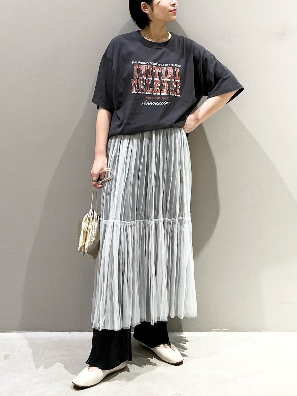 ブラック系のデニムパンツ、グレー系のスカート、ゴールド系のハンドバッグを着用したレディースの夏コーディネートの2枚目の写真