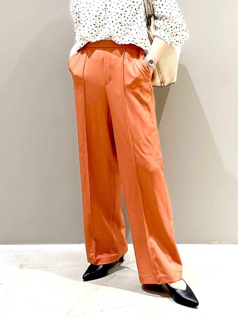 ホワイト系のシャツ/ブラウス、オレンジ系のスラックス、ブラック系のパンプスを着用したレディースの秋コーディネートの3枚目の写真