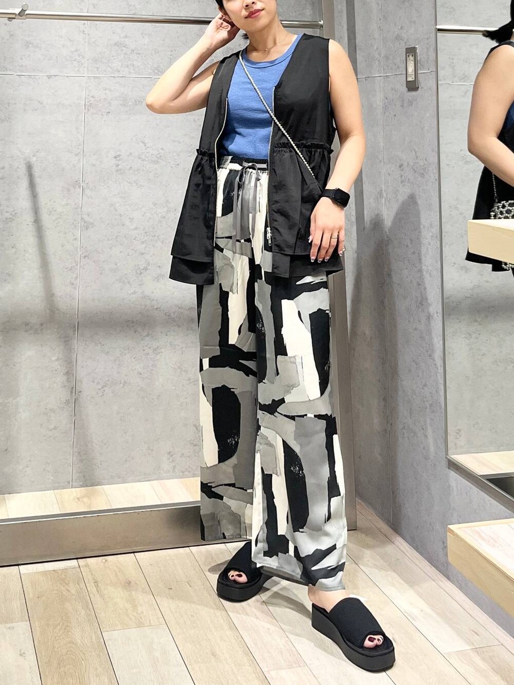 ブルー系のTシャツ/カットソー、ブラック系のサンダル、ブラック系のベストを着用したレディースの夏コーディネートの4枚目の写真